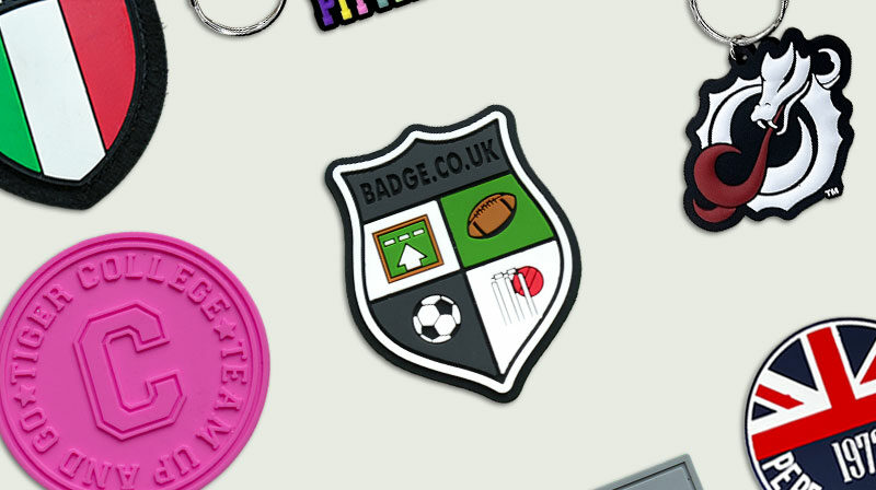 Collection of PVC badges and keyrings in assorted shapes including round shield and rectangular design